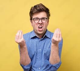 a white male standing before a yellow background complaining