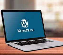 a laptop sitting on a table top with the word 'WordPress' on the screen